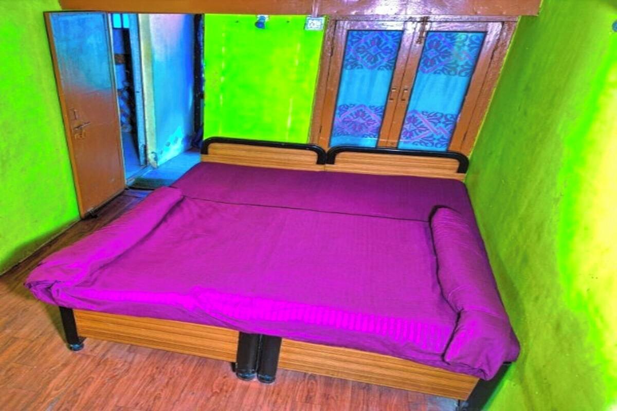 A small room with a bed, wooden floor, and green walls.