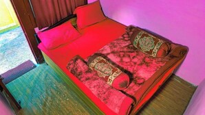 Una cama con ropa de cama roja, un cabecero de madera y almohadas estampadas.