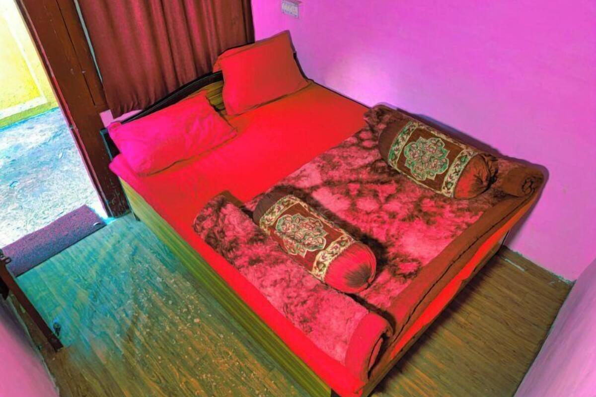 A bed with red bedding, a wooden headboard, and patterned pillows.