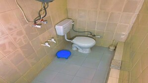Un baño pequeño con inodoro, un bidé azul y un cepillo de inodoro.