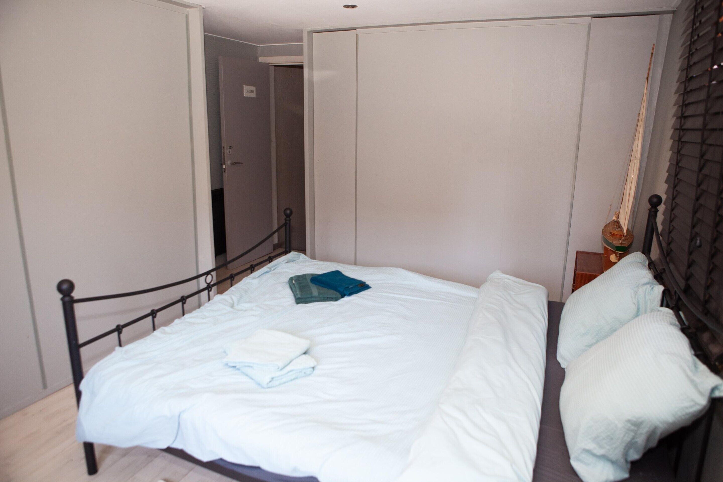 A bedroom with a bed, a wardrobe, and a nightstand.