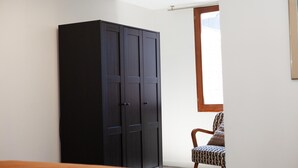 Ein Schlafzimmer mit Kleiderschrank, Stuhl und Fenster.