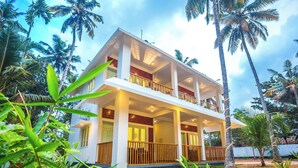 Un edificio de dos pisos con balcones, rodeado de palmeras y follaje.