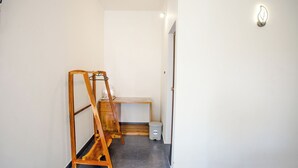 Un pasillo con una escalera de madera, una mesita y un cubo de basura.