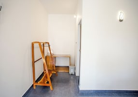 Un pasillo con una escalera de madera, una mesita y un cubo de basura.