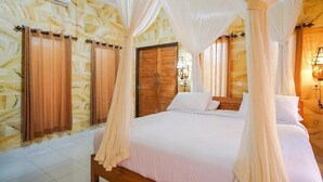 A bedroom with a four-poster bed, wooden doors, and a stone-patterned wall. - Mejan Beach Home Stay (Selemadeg)