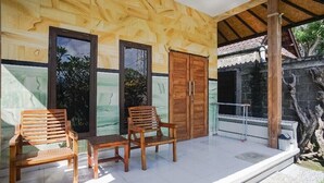 A wooden exterior with a covered patio, two wooden chairs, and a table. - Mejan Beach Home Stay (Selemadeg)