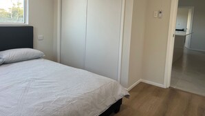 Et soveværelse med seng, skab, et vindue og en dør til et badeværelse.