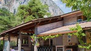 A rustic wooden building with a covered patio, a hanging plant basket, and a chalkboard menu.