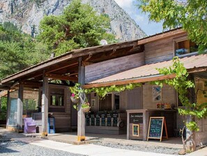A rustic wooden building with a covered patio, a hanging plant basket, and a chalkboard menu.