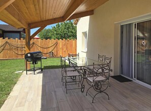 A covered patio with a table and chairs, a grill, and a sliding glass door. - House with AC, pets welcome - 6 guests (Lalinde)