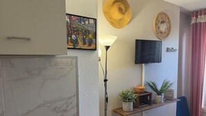 En moderne stue med en marmorpejs, et ophængt fjernsyn, en gulvlampe og en reol med pynteting.