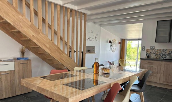 Une cuisine moderne avec un escalier en bois, une table à manger avec des chaises et un îlot de cuisine.