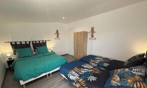 Une chambre à coucher avec un lit, des tables de chevet, une armoire et une porte.
