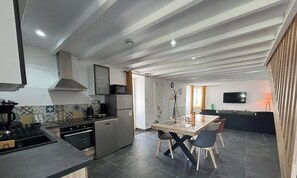 Une cuisine moderne avec un coin repas, un téléviseur et une fenêtre avec des rideaux.