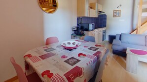 A compact living space with a dining area, kitchenette, and a staircase.
