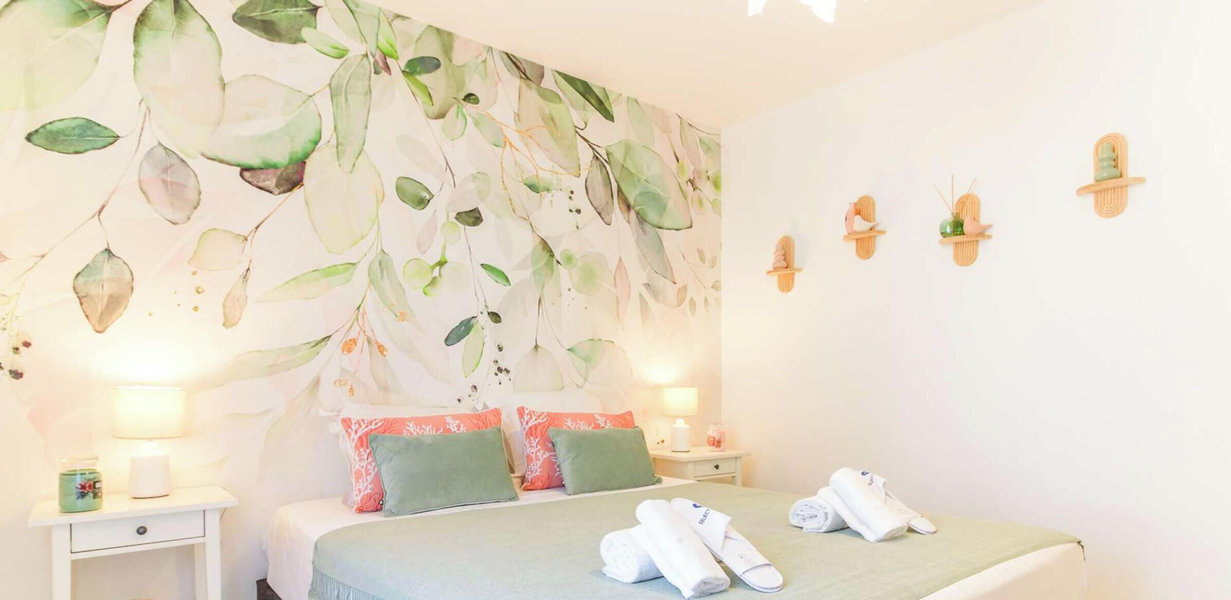 Une chambre d’hôtel comprenant un lit, deux tables de chevet, une étagère fixée au mur et un élément décoratif mural.