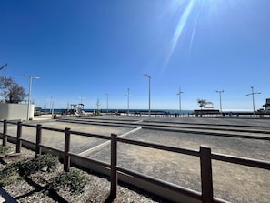 A coastal promenade with a clear sky, a metal railing, and a playground. - Quiet studio, garden view - 4 guests (Cap d'Agde)