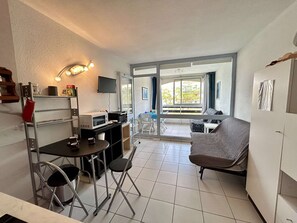 A compact living space with a kitchenette, dining area, and a sofa. - Quiet studio, garden view - 4 guests (Cap d'Agde)