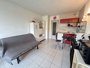 Un espace de vie compact comprenant un canapé, une kitchenette et un petit coin repas.
