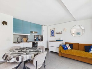 A compact living space with a kitchenette, dining area, and a sofa. - Apartment with AC and WiFi - 5 guests - In the village center (Le Grau d'Agde)