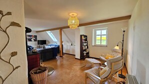 Una sala de estar acogedora con chimenea, una estantería y un comedor.