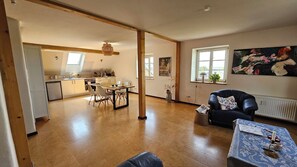 Un amplio salón con una mesa de comedor, un sofá y una cocina al fondo.