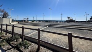 Eine Uferpromenade mit blauem Himmel, Metallgeländern und Straßenlaternen.