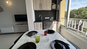 Eine kompakte Küche mit Mikrowelle, einem kleinen Kühlschrank und einer Essecke mit Tisch für zwei Personen.