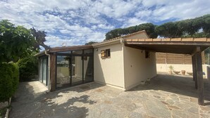Ein Haus mit Glastür, einer Steinterrasse und einer Pergola.