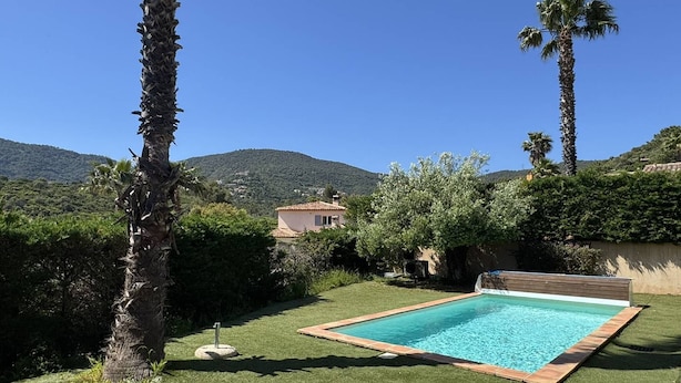 A swimming pool with a view of a mountain, surrounded by palm trees and a small building. - Quiet villa with air conditioning and pool (Cavalaire-sur-Mer)