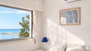 Ein Schlafzimmer mit Bett, einem Fenster mit Meerblick, einer Wand-Klimaanlage und einer Lampe.