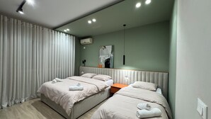 A modern hotel room with two beds, a wooden floor, an air conditioning unit, and a painting on the wall. - Zest Premium Apartments 2 (Durrës)