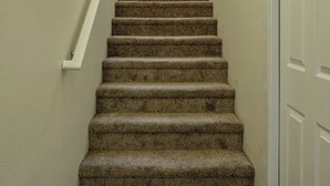 A carpeted staircase with a handrail and wall-mounted light fixtures, leading to a door with a window above. - 4 Bed 3 Bath House In With Movie Theatre FREE WIFI (Gold Hill)