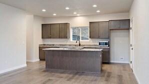 A kitchen with a central island, dark wooden cabinets, and a microwave. - 4 Bed 3 Bath House In With Movie Theatre FREE WIFI (Gold Hill)
