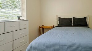 A bedroom with a bed, a dresser, a nightstand, and a window with blinds. - 4 Bed 3 Bath House In With Movie Theatre FREE WIFI (Gold Hill)