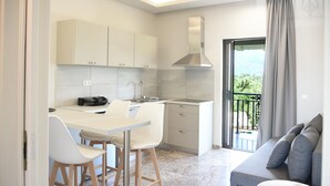 A modern kitchen with white cabinets, a built-in oven, and a dining area with white chairs.