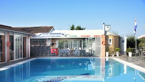 A swimming pool with a bar area, a restaurant, and a flag.
