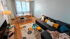 A modern living room with a sofa, a dining table set for four, a TV, and a lamp. - Spacious T4 with views of the Alps (Seyssinet-Pariset)