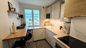A compact kitchen with a window, built-in appliances, and a dining area. - Spacious T4 with views of the Alps (Seyssinet-Pariset)