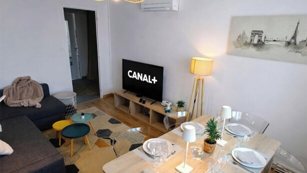 A modern living room with a sofa, a TV, a dining table set, and a lamp. - Spacious T4 with views of the Alps (Seyssinet-Pariset)