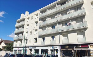 A multi-story building with balconies, storefronts, and parked cars. - Spacious T4 with views of the Alps (Seyssinet-Pariset)