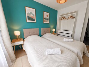 A hotel room with two beds, a nightstand with a lamp, a wardrobe, and two framed pictures on the wall. - Spacious T4 with views of the Alps (Seyssinet-Pariset)