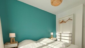 A bedroom with teal walls, two beds with white bedding, a bedside table with a lamp, and a wardrobe with a mirror. - Spacious T4 with views of the Alps (Seyssinet-Pariset)