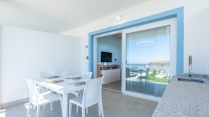 A balcony with a dining table and chairs, a TV, and a view of a building. - Affittimoderni Trinity D'Agultu - Aquamarine (Trinità d´Agultu e Vignola)