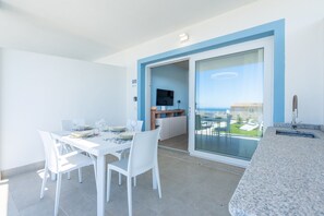 A balcony with a dining table and chairs, a TV, and a view of a building. - Affittimoderni Trinity D'Agultu - Aquamarine (Trinità d´Agultu e Vignola)