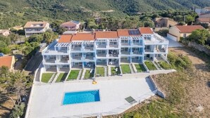 A multi-story hotel with a swimming pool, surrounded by greenery and hills. - Affittimoderni Trinity D'Agultu - Aquamarine (Trinità d´Agultu e Vignola)
