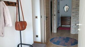 A hallway with a bench, a coat rack, a shoe rack, and a door leading to another room. - La Corsica (Sillans-la-Cascade)