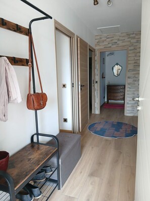 A hallway with a bench, a coat rack, a shoe rack, and a door leading to another room. - La Corsica (Sillans-la-Cascade)