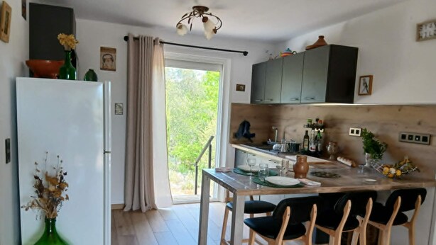 A kitchen with a dining area, a refrigerator, and a window with curtains. - La Corsica (Sillans-la-Cascade)